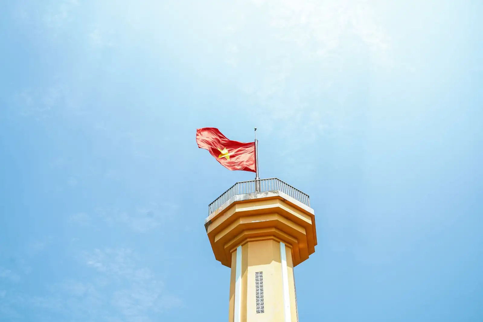 Vietnamese flag waving atop a monument tower under a clear blue sky on Ly Son Island.